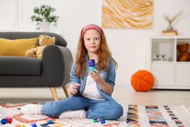 Photo of Little girl playing with balancing stones on floor indoors