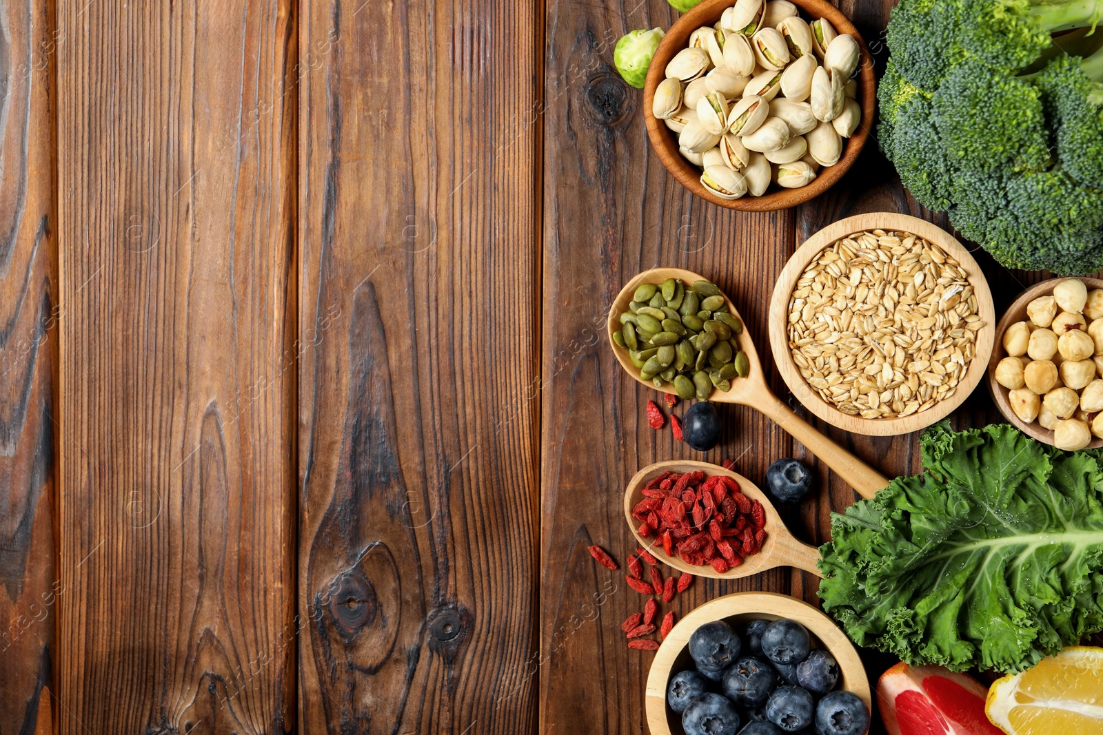 Photo of Different superfood products on wooden table, flat lay. Space for text