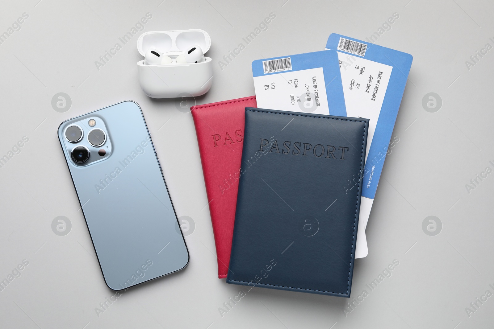 Photo of Travel agency. Flight tickets, passports, smartphone and earphones on grey background, flat lay