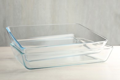 Photo of Glass casseroles on light wooden table, closeup