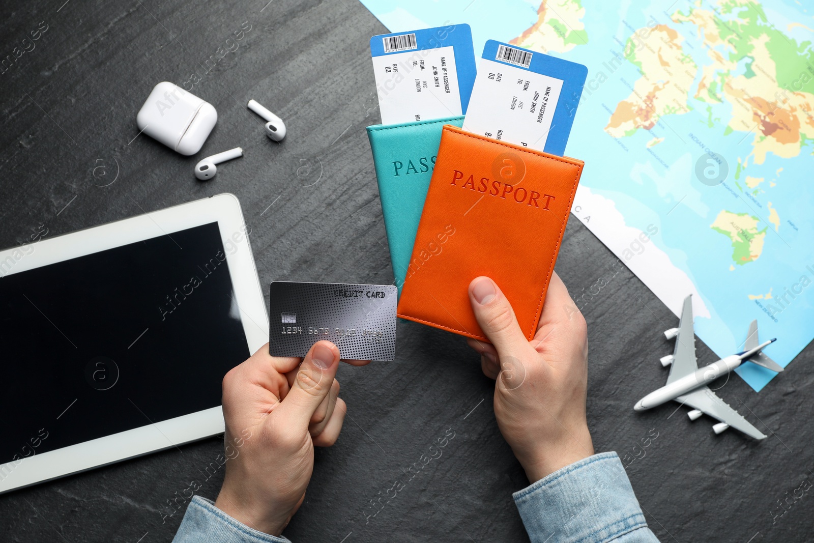 Photo of Travel agency. Man with passports, flight tickets and credit card at dark textured table, top view