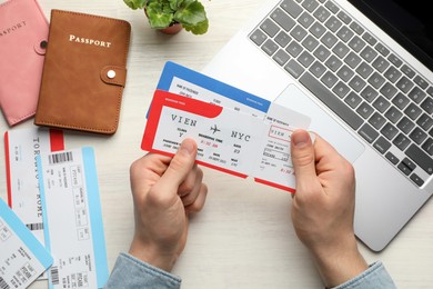 Photo of Travel agency. Man with flight tickets at light wooden table, top view