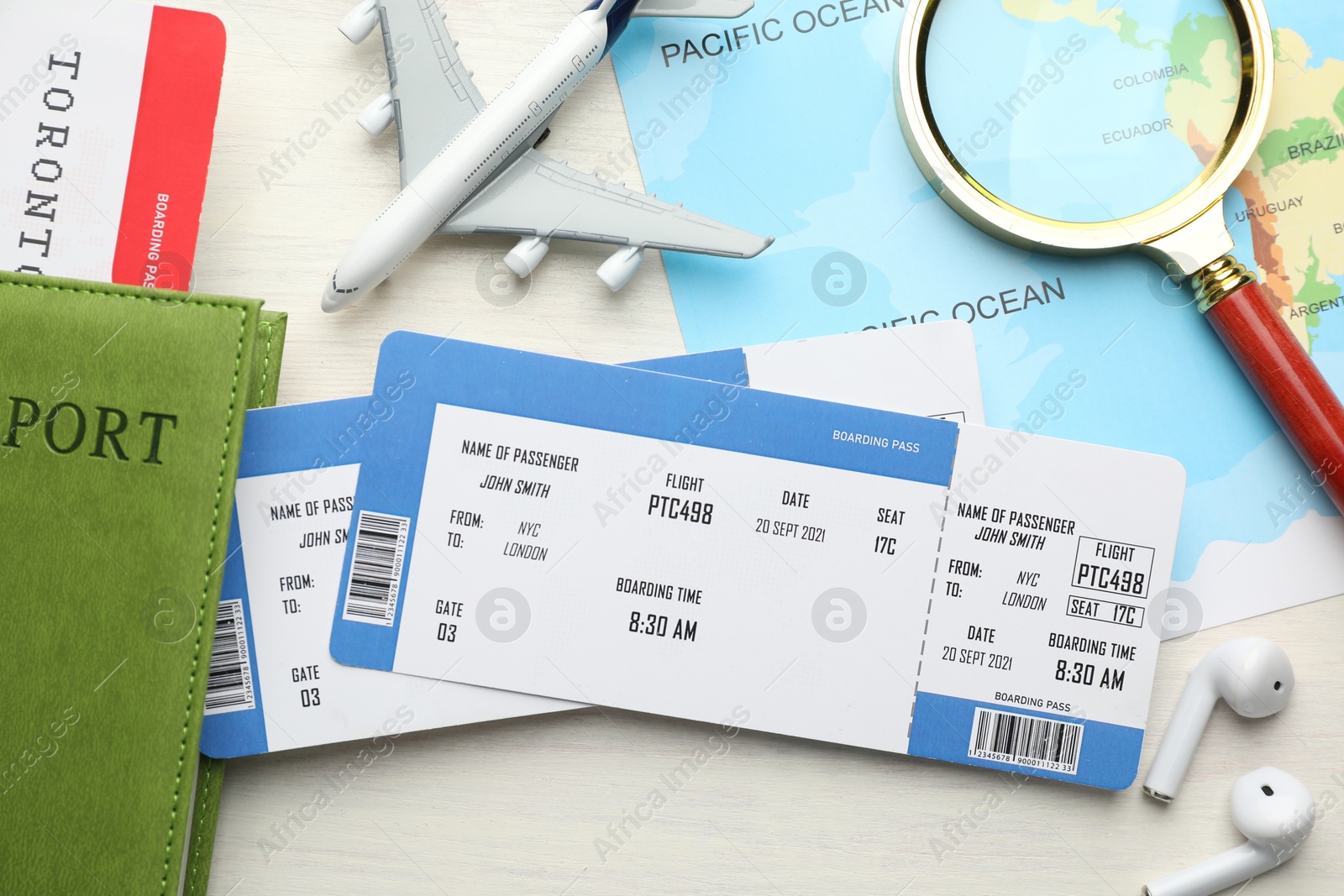 Photo of Travel agency. Flat lay composition with flight tickets and magnifying glass on light wooden table