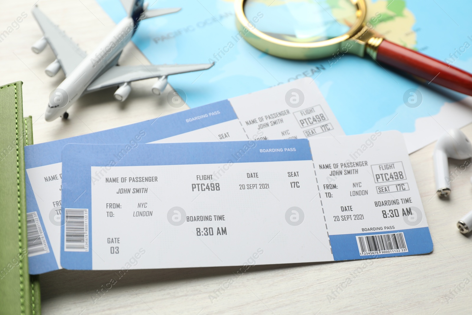 Photo of Travel agency. Flight tickets, plane model and magnifying glass on light wooden table, closeup