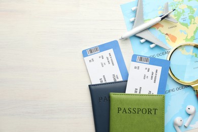 Photo of Travel agency. Flight tickets, passports, world map and plane model on light wooden table, flat lay. Space for text