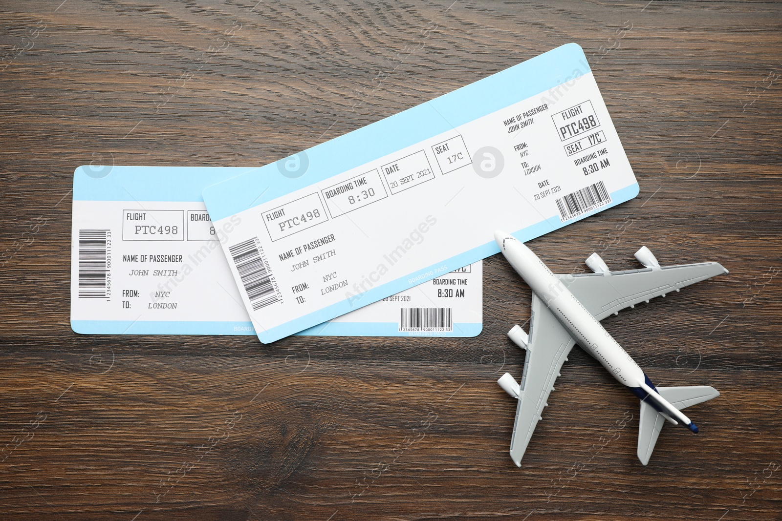 Photo of Travel agency. Flight tickets and plane model on wooden table, flat lay