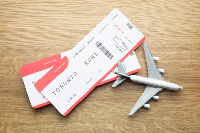 Photo of Travel agency. Flight tickets and plane model on wooden table, flat lay