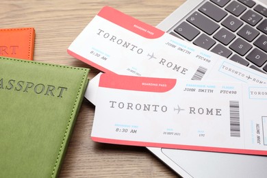 Photo of Travel agency. Flight tickets, passport and laptop on wooden table, closeup