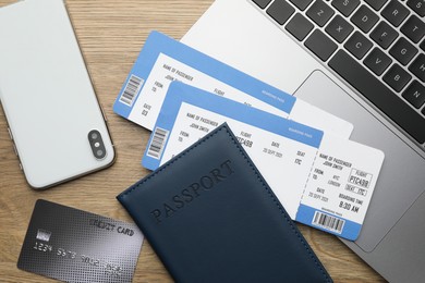 Photo of Travel agency. Flight tickets, passport, credit card, smartphone and laptop on wooden table, flat lay