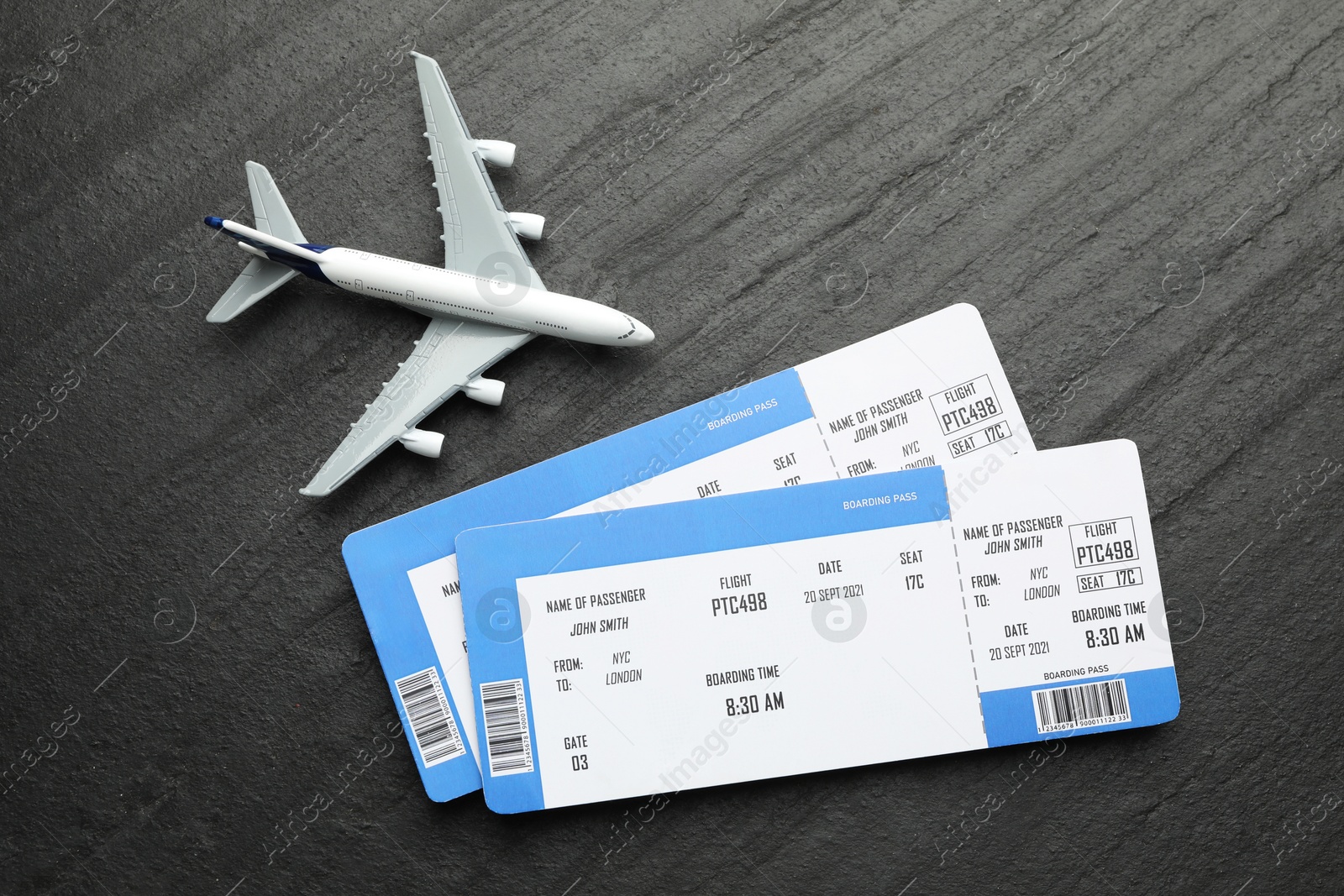 Photo of Travel agency. Flight tickets and plane model on dark textured table, flat lay