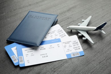 Photo of Travel agency. Flight tickets, passport and plane model on dark textured table, closeup