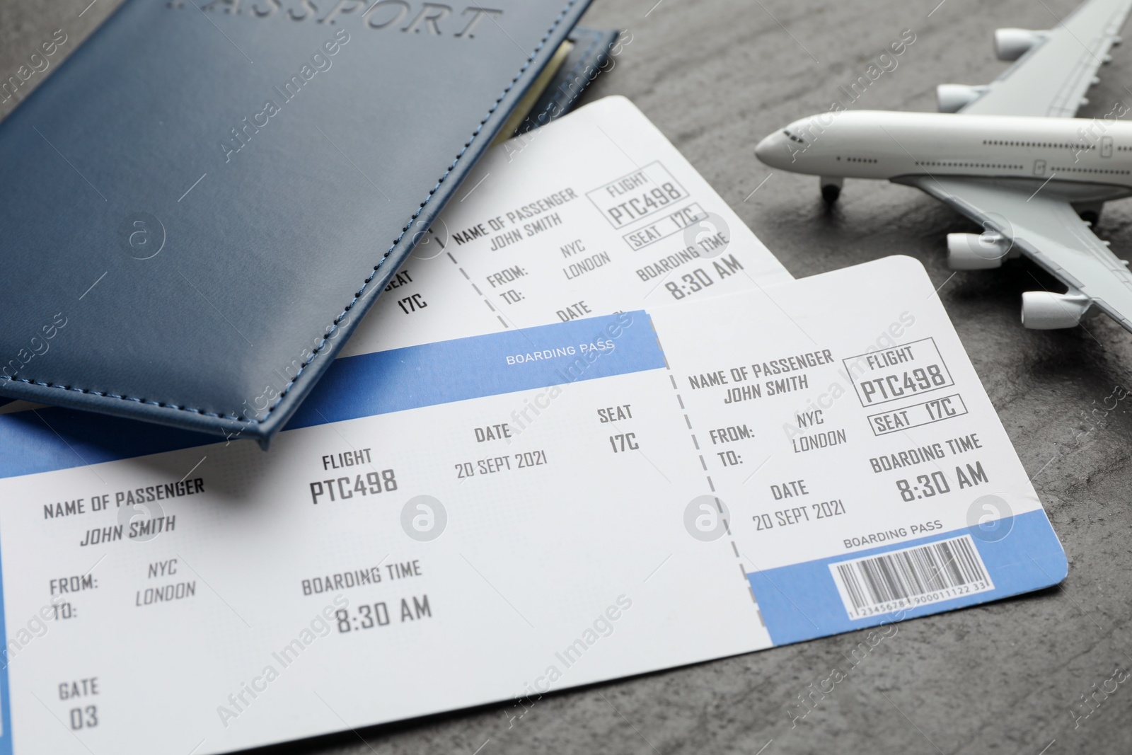 Photo of Travel agency. Flight tickets, passport and plane model on dark textured table, closeup