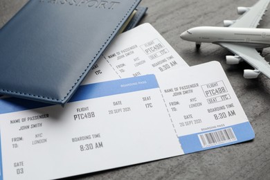 Photo of Travel agency. Flight tickets, passport and plane model on dark textured table, closeup