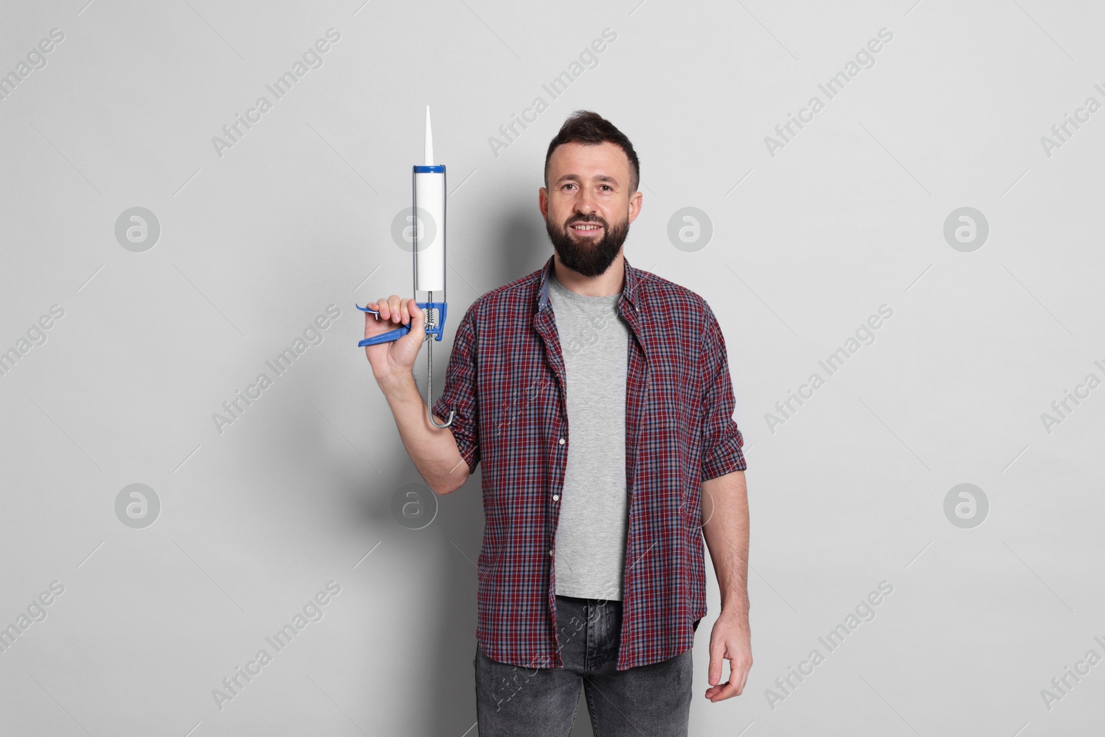 Photo of Man with caulking gun on gray background