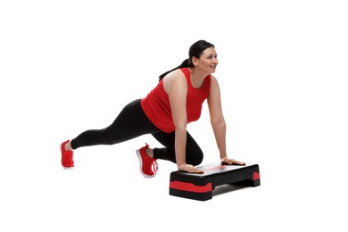 Photo of Plus size woman in gym clothes doing exercise with step platform on white background