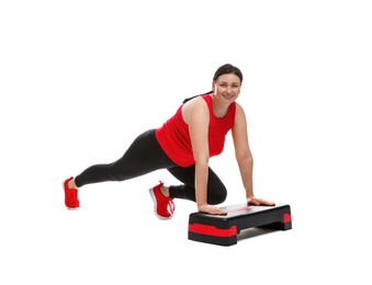 Photo of Plus size woman in gym clothes doing exercise with step platform on white background