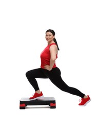 Photo of Plus size woman in gym clothes doing exercise with step platform on white background