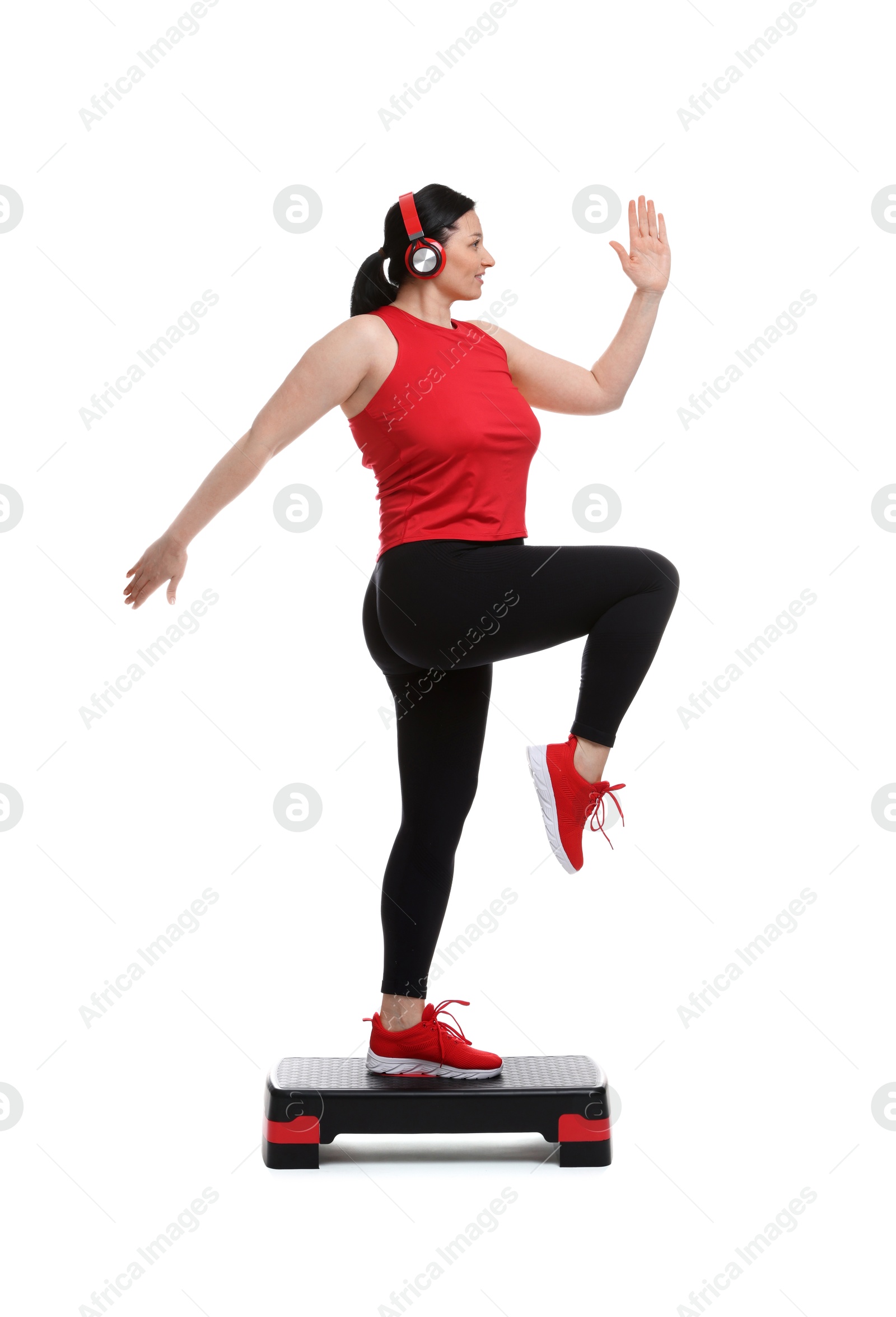 Photo of Plus size woman in gym clothes doing exercise with step platform on white background