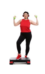 Photo of Plus size woman in gym clothes doing exercise with step platform and dumbbells on white background