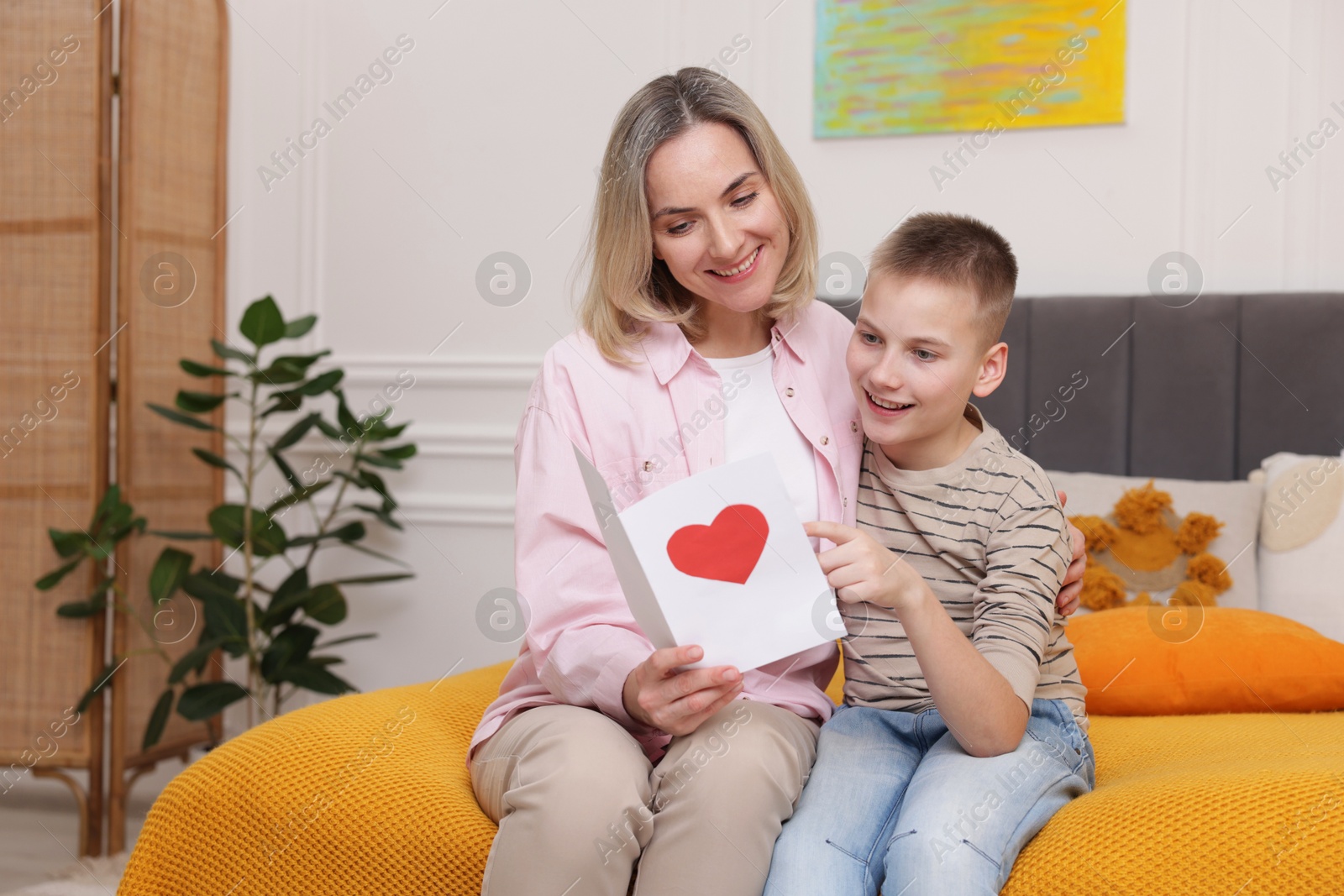 Photo of Happy Mother's Day. Son greeting his mom with card on bed indoors