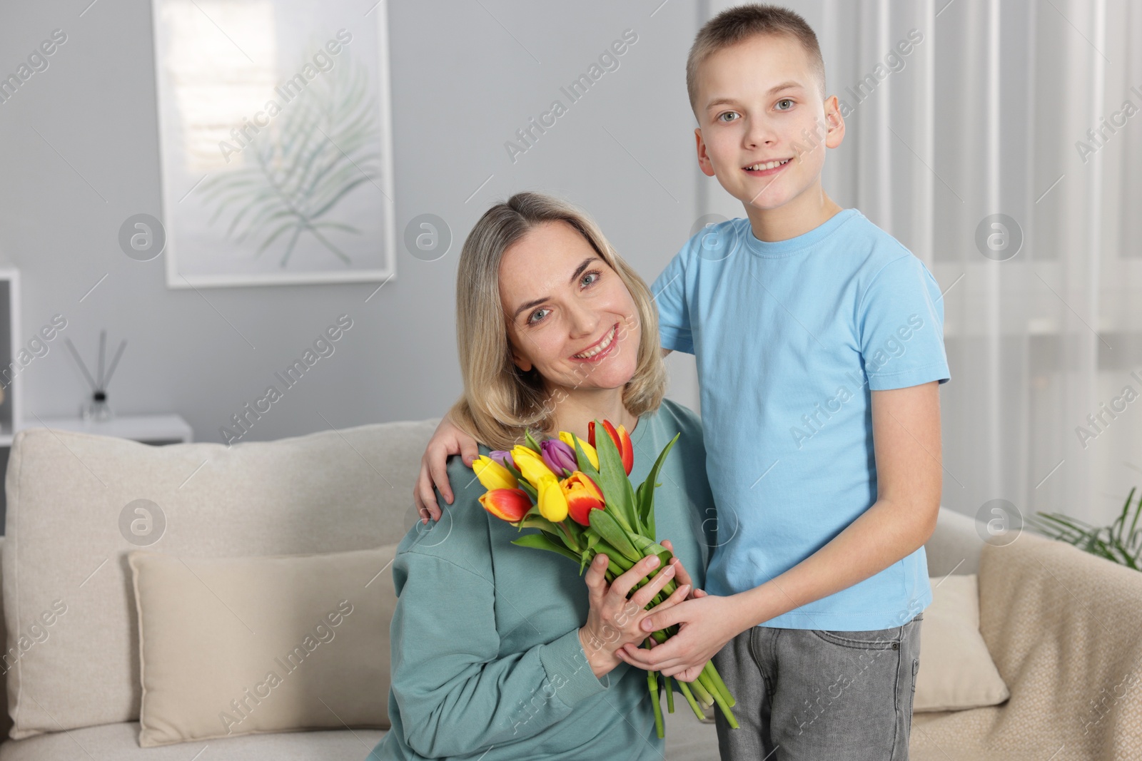 Photo of Happy Mother's Day. Son greeting his mom with flowers at home. Space for text