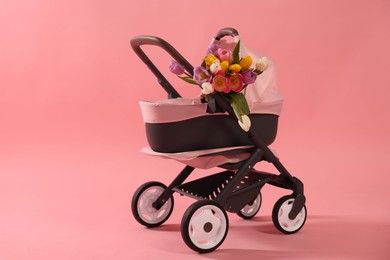 Photo of Stylish doll stroller and tulips on pink background. Kid's toy