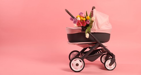 Photo of Stylish doll stroller and tulips on pink background, space for text. Kid's toy