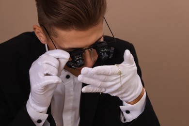 Photo of Appraiser evaluating luxury jewelry on brown background