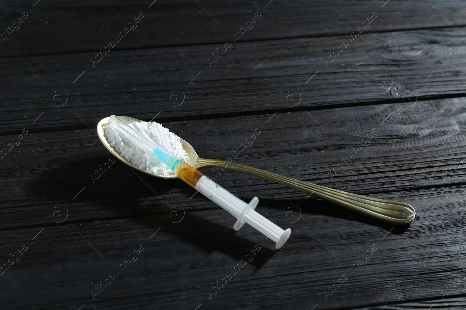 Photo of Drug addiction. Spoon with powder and syringe on black wooden table