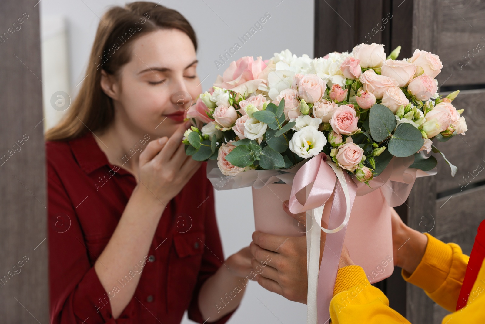 Photo of Woman smelling beautiful flowers from delivery man at door