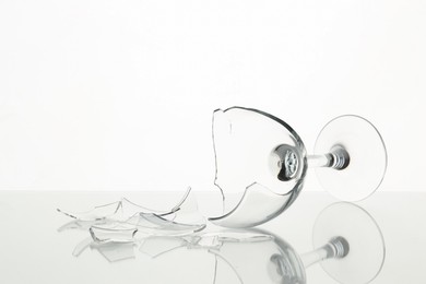 Photo of Pieces of broken wine glass on table against white background