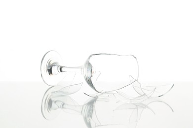 Photo of Pieces of broken wine glass on table against white background