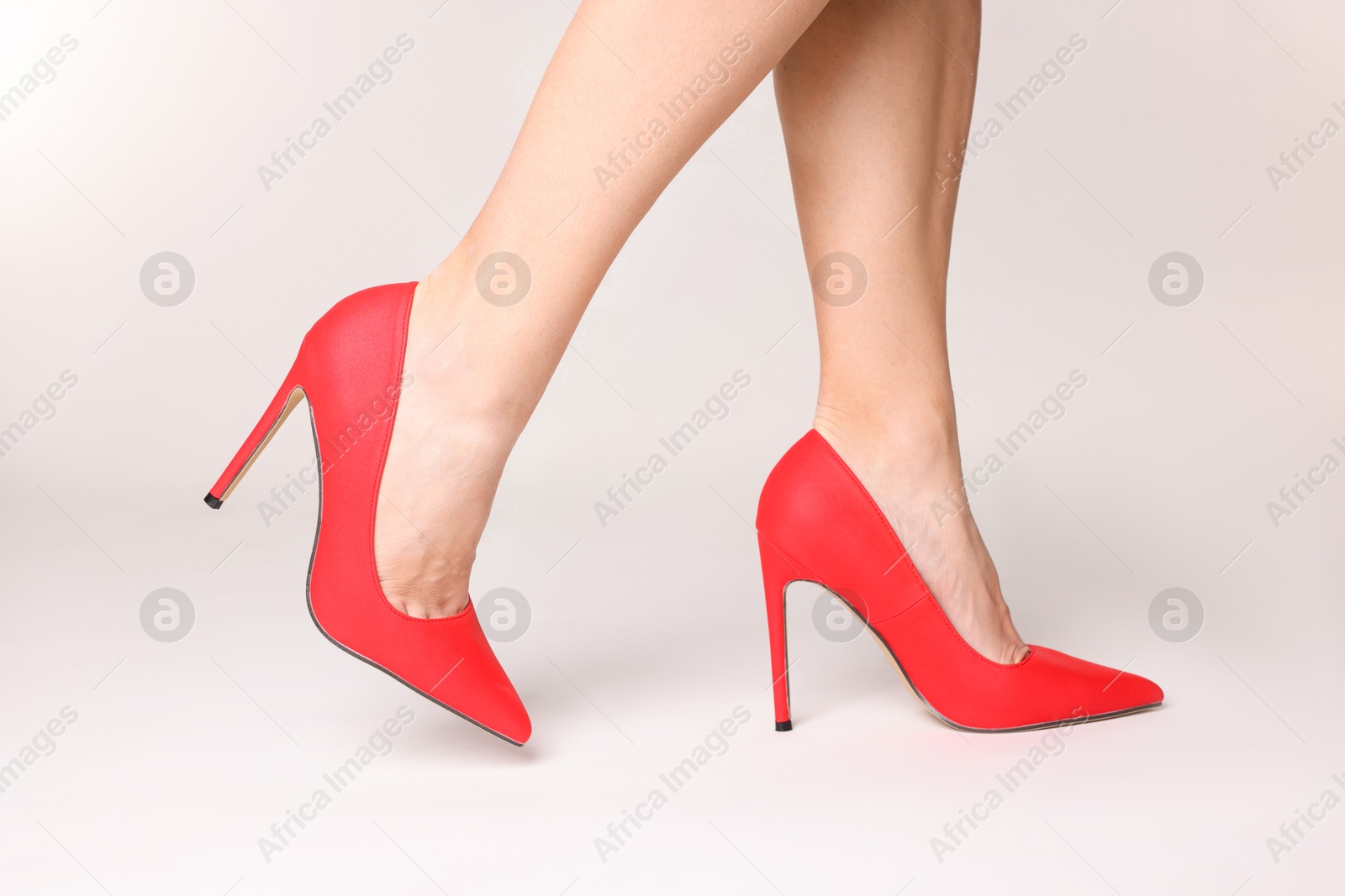 Photo of Woman wearing beautiful red high heeled shoes on white background, closeup