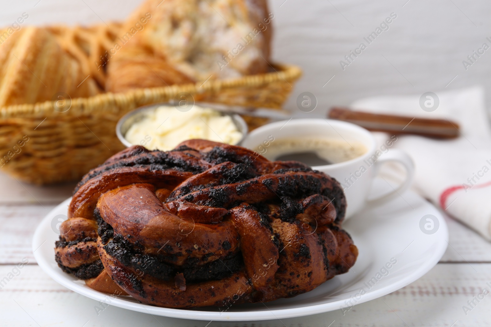 Photo of Delicious poppy seed pastry, butter and coffee on white wooden table, closeup