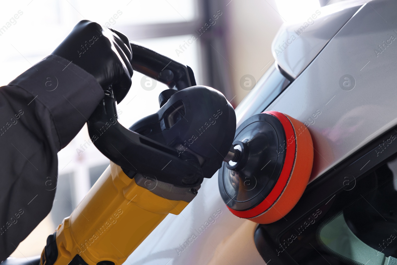 Photo of Man polishing car with orbital polisher indoors, closeup