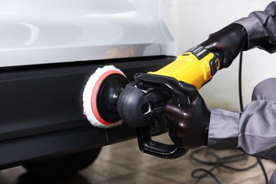 Photo of Man polishing car with orbital polisher indoors, closeup