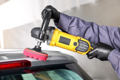 Photo of Man polishing car with orbital polisher indoors, closeup