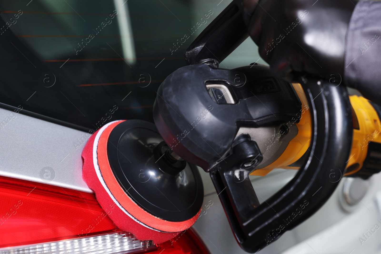 Photo of Man polishing car with orbital polisher indoors, closeup