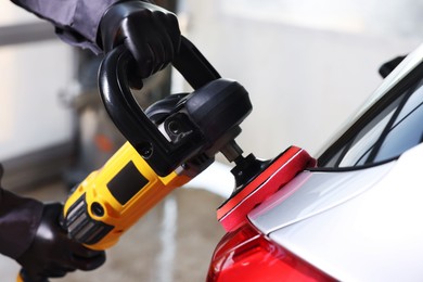 Photo of Man polishing car with orbital polisher indoors, closeup