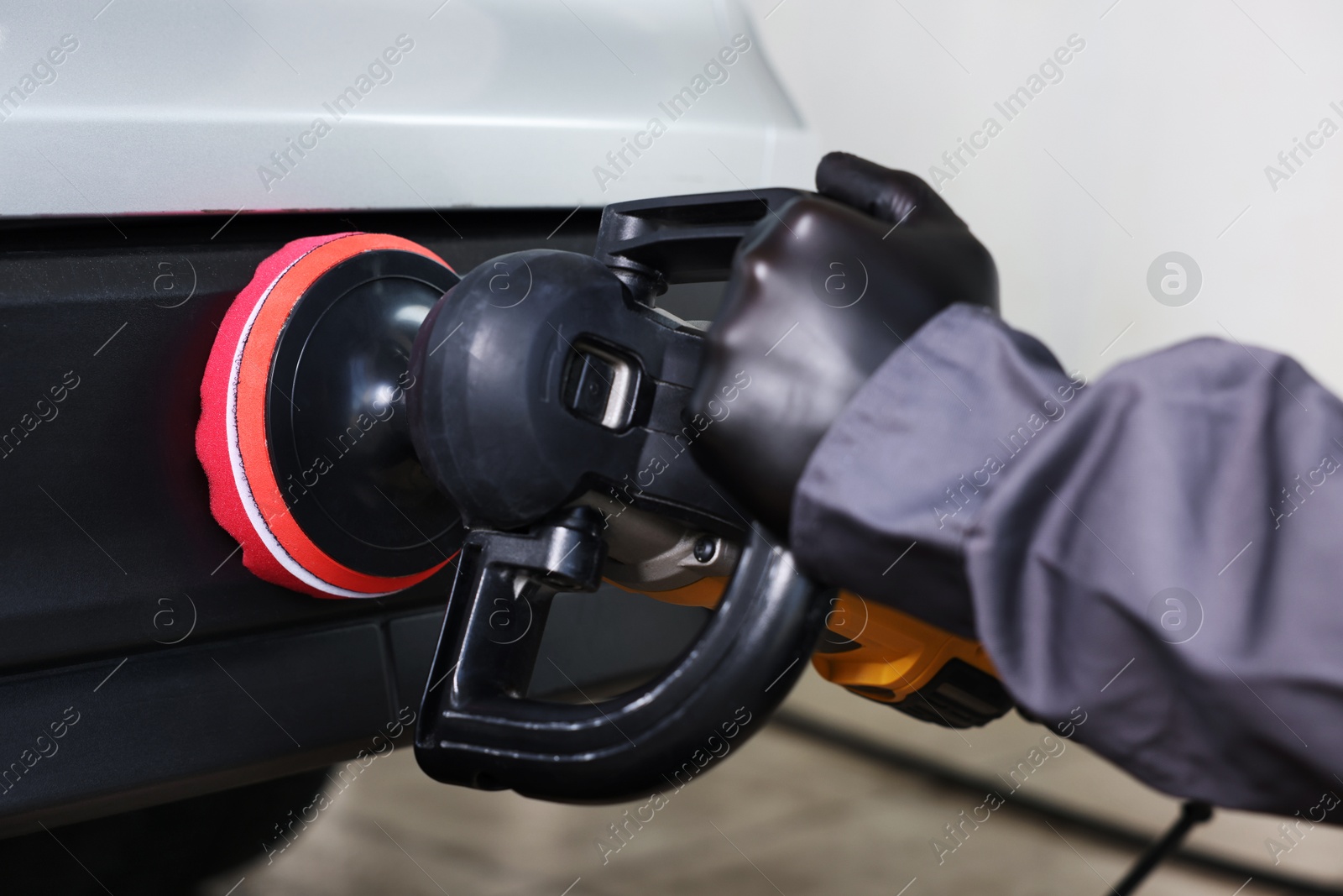 Photo of Man polishing car with orbital polisher indoors, closeup