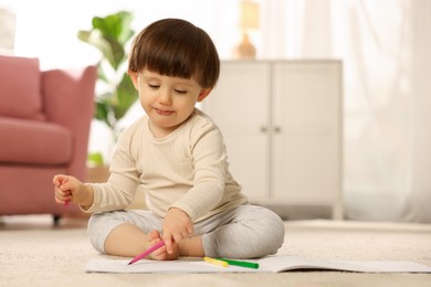 Photo of Cute little boy drawing on floor at home, space for text