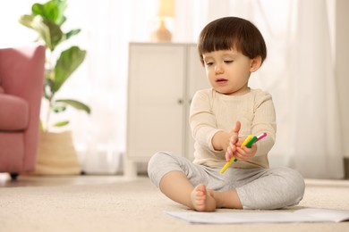 Photo of Cute little boy with felt pens on floor at home, space for text