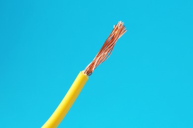 Photo of Stripped electrical wire with copper strands on light blue background, space for text