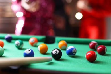 Photo of Many colorful billiard balls and cue on green table indoors, closeup. Space for text