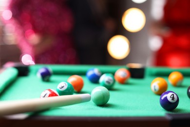 Photo of Many colorful billiard balls and cue on green table indoors, closeup. Space for text