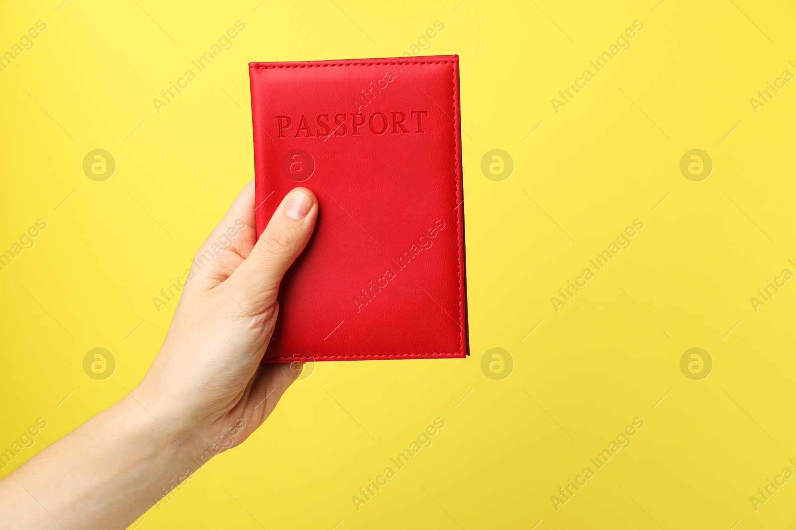 Photo of Woman holding passport in bright cover on yellow background, closeup. Space for text