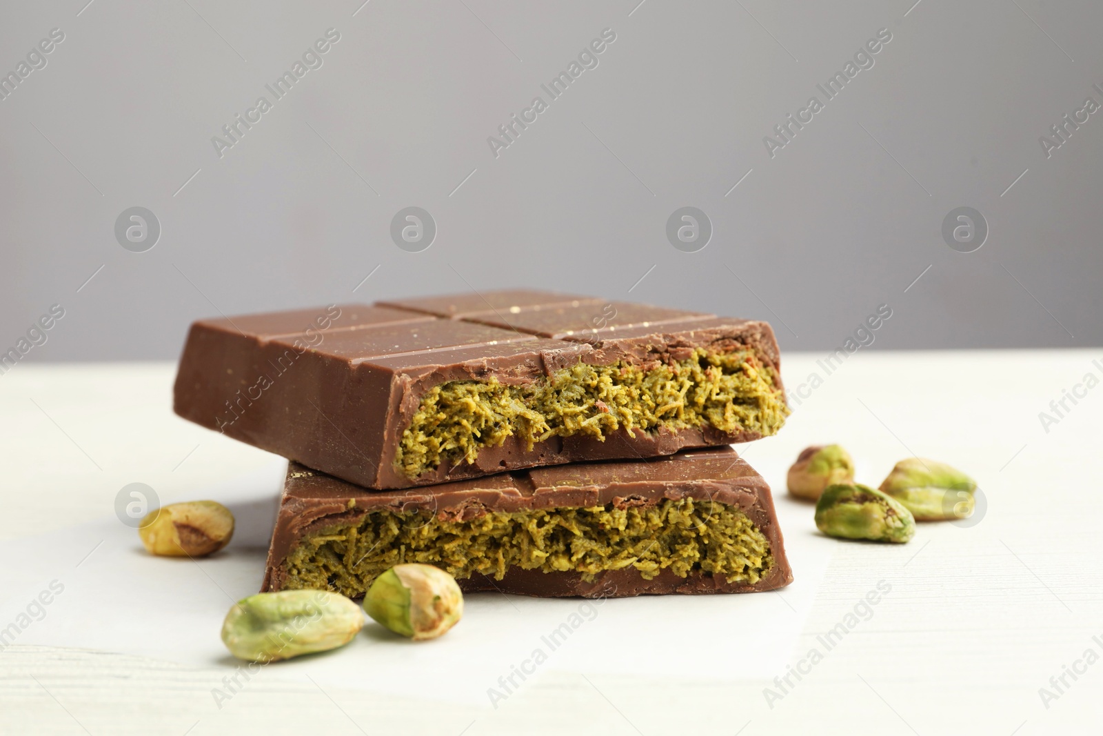 Photo of Pieces of tasty Dubai chocolate with pistachios and knafeh on white wooden table, closeup