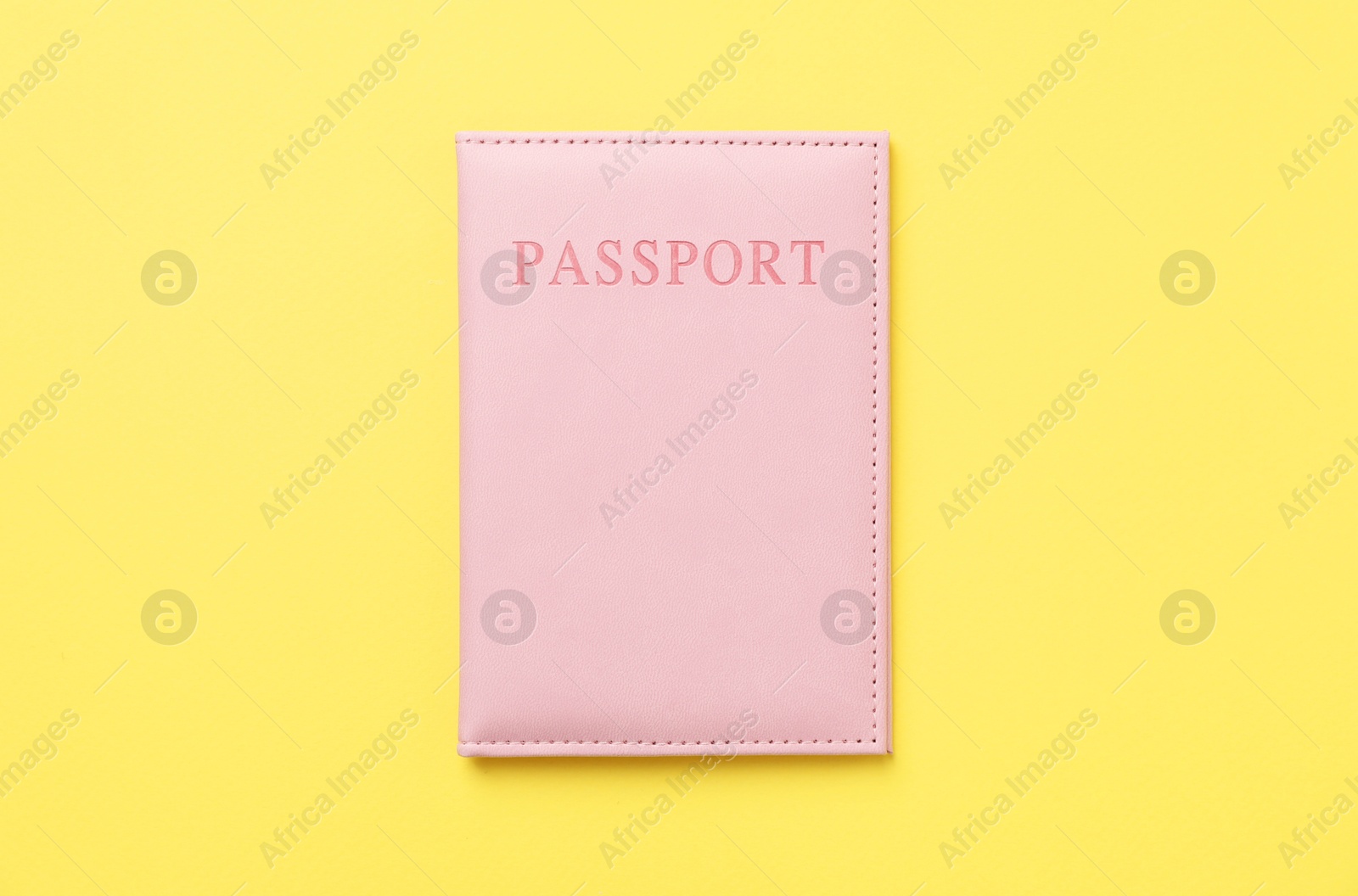 Photo of Passport in bright cover on yellow background, top view