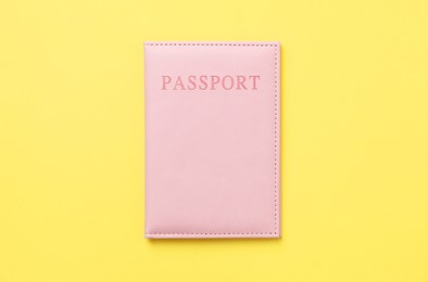 Photo of Passport in bright cover on yellow background, top view