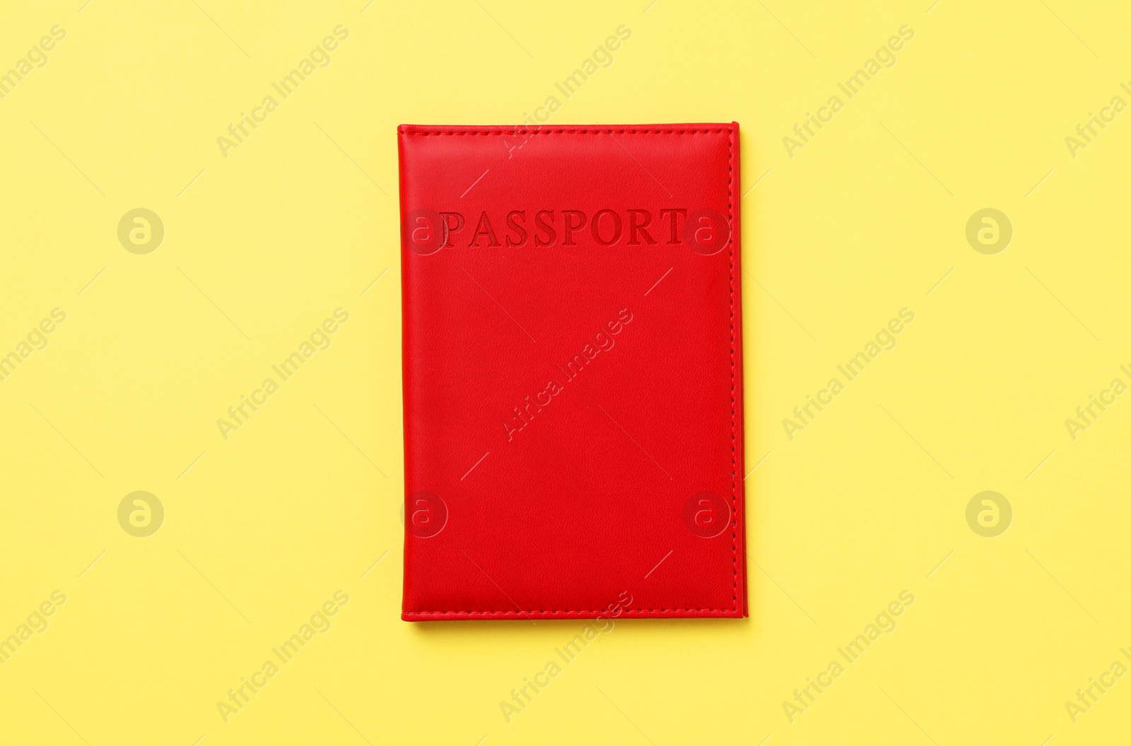 Photo of Passport in bright cover on yellow background, top view